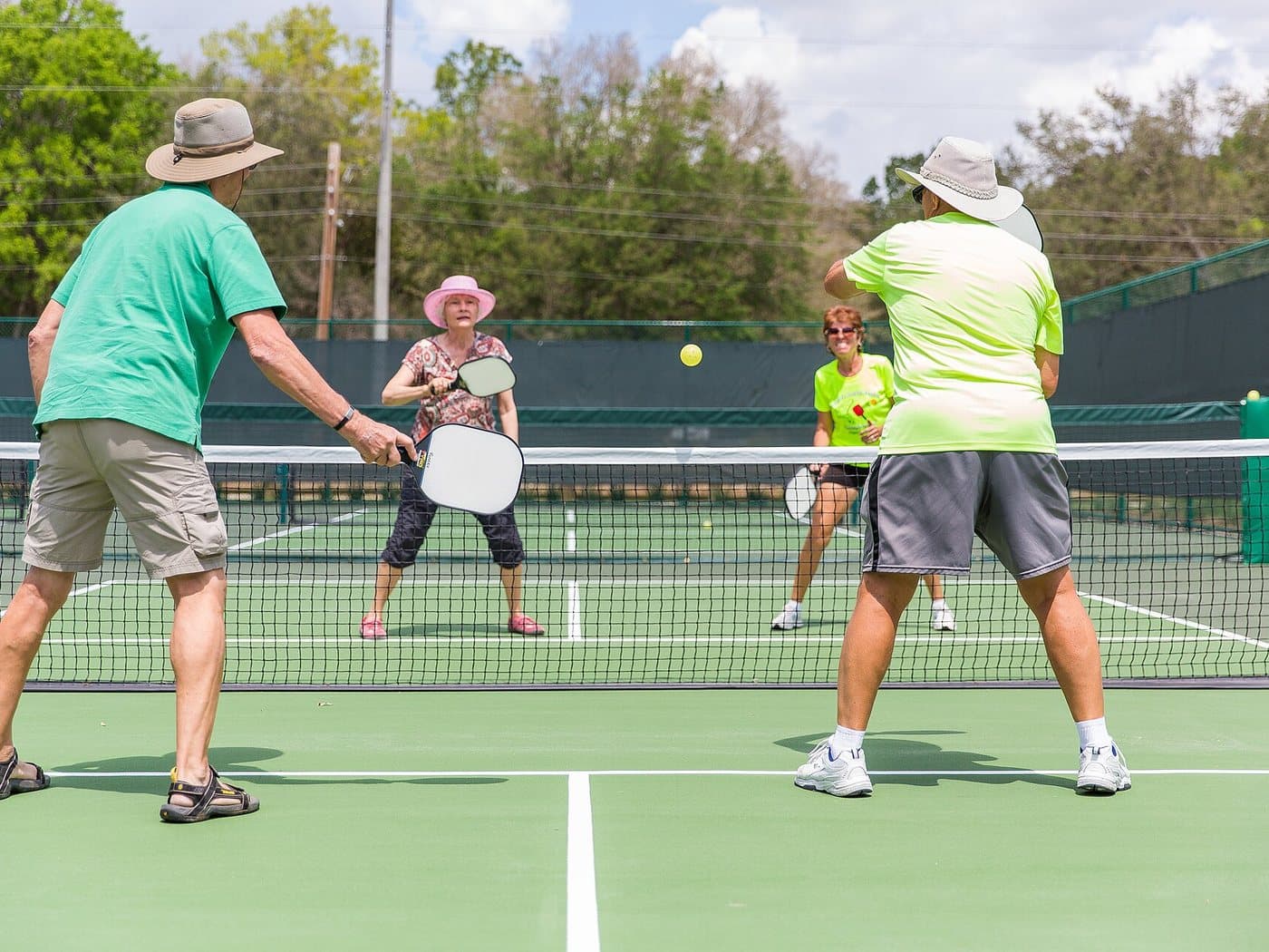 Four people playing doubles pickleball on an outdoor court